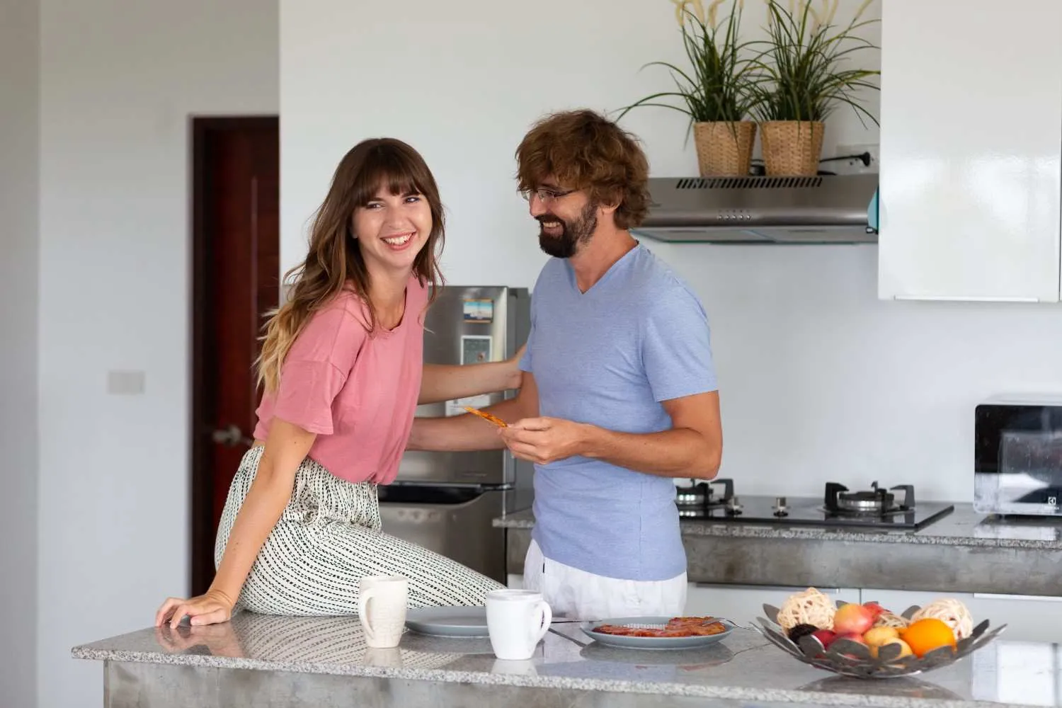 Two homeowners smiling in their kitchen beside the refrigerator and stove